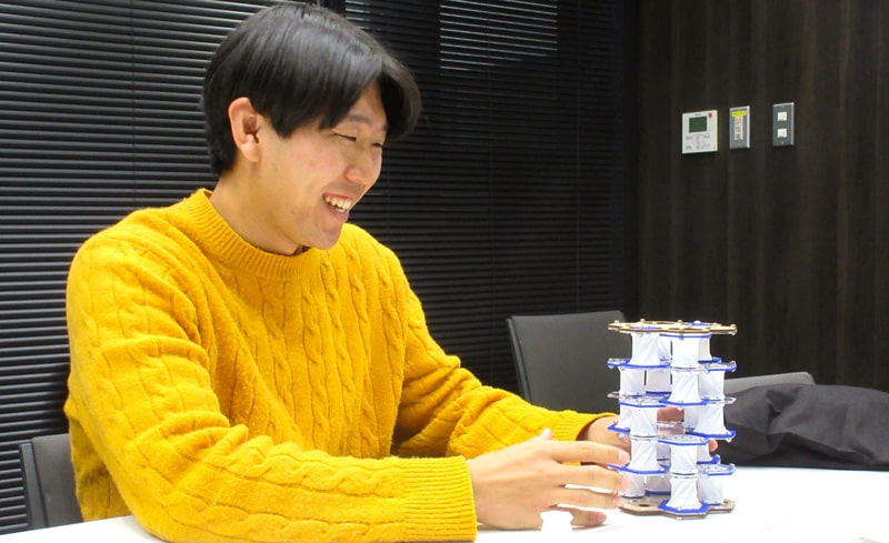Kresling折り紙を応用した展開構造（展開状態）を持ち、説明する岡崎氏